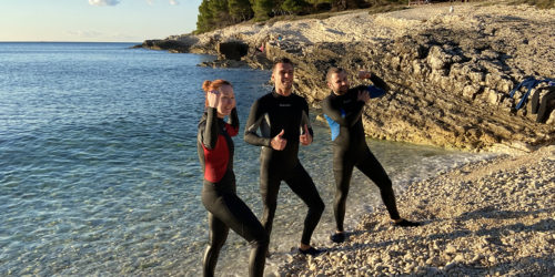 three people in wetsuits on beach