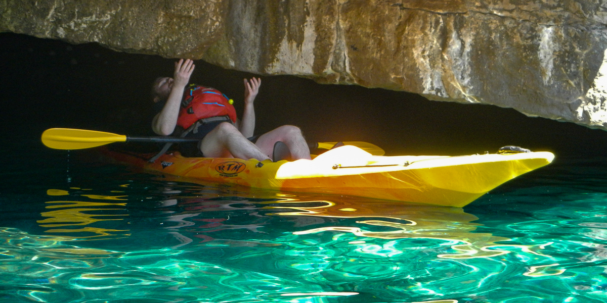 Man in the kayak under the rock