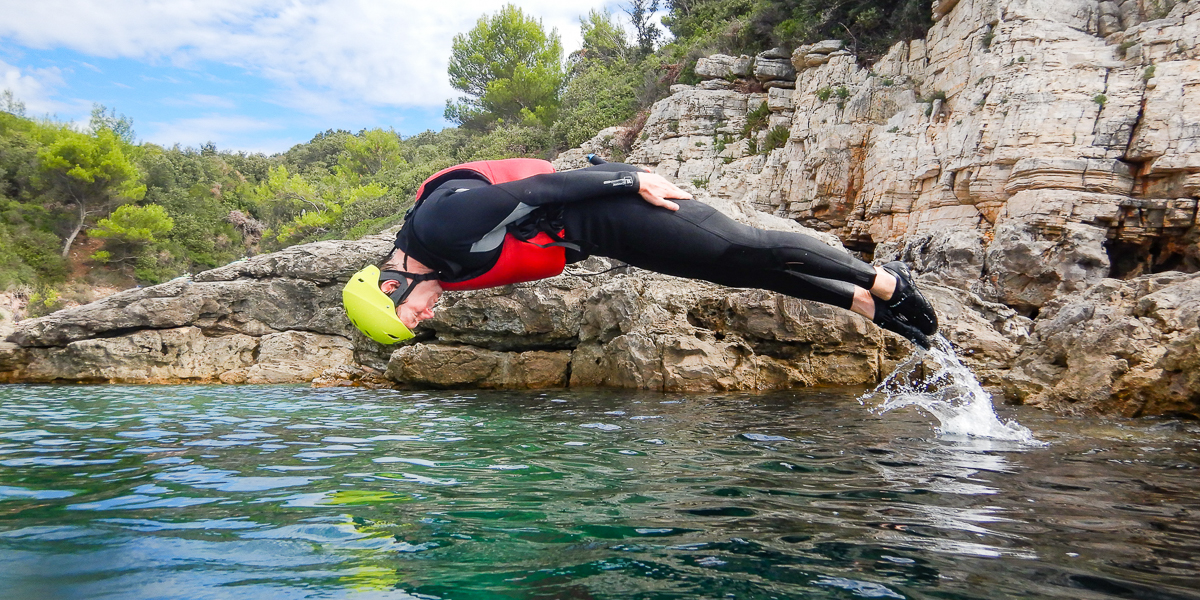 Man jumping from rock into the sea head first.