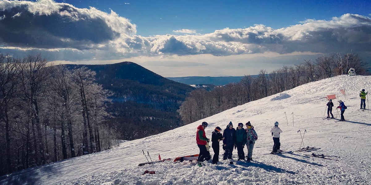 A group of snowboarders taking photos on top of the mountain covered with snow.