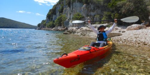 Person in a kayak near rocky shore with cliffs in Lim, Istria, Croatia.